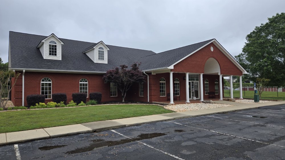 Exterior view of a red brick veterinary clinic featuring a large front porch, ample parking, and professional curb appeal. - Veterinarian in Jefferson, GA